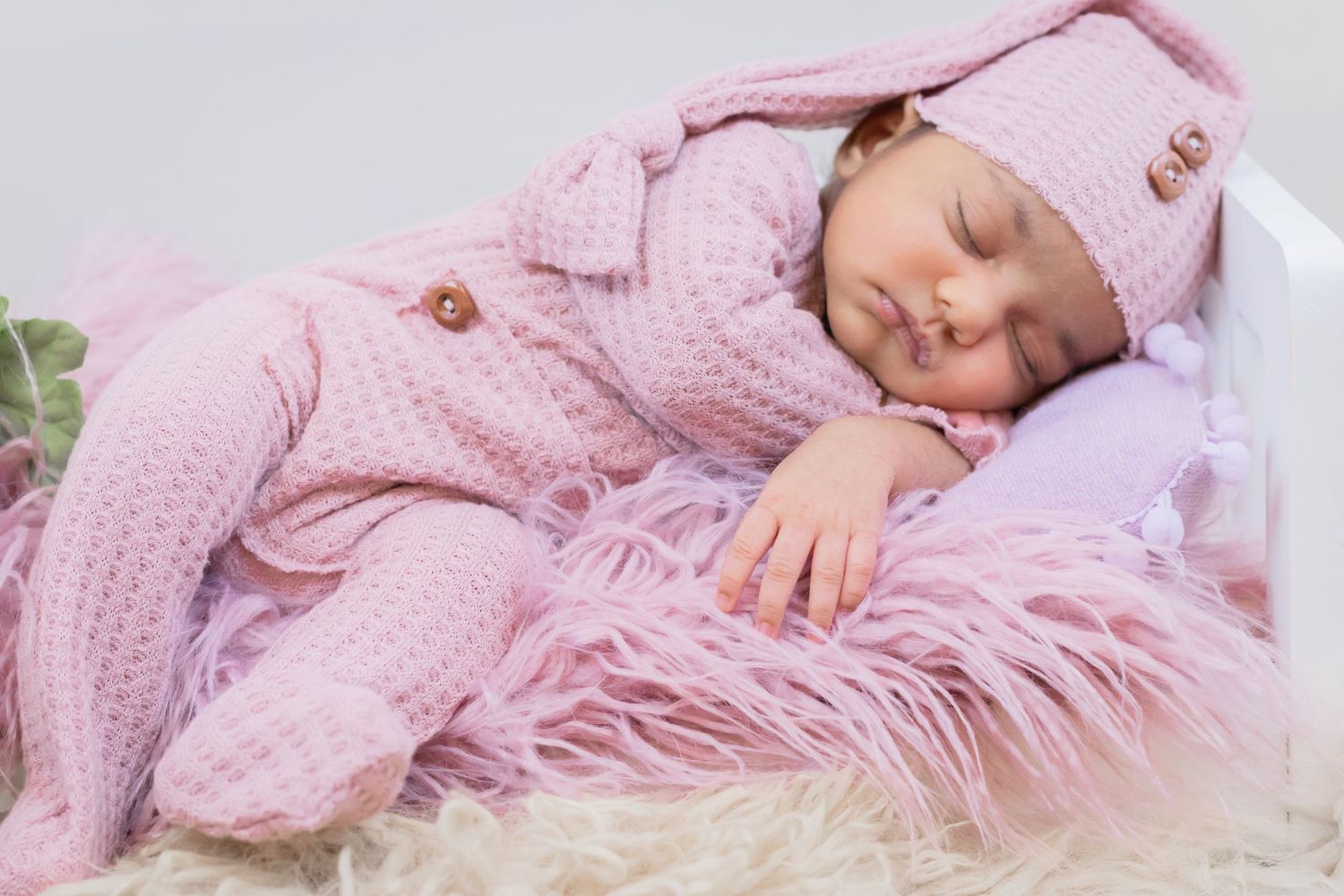 a beautiful sleeping baby rests on a white bed