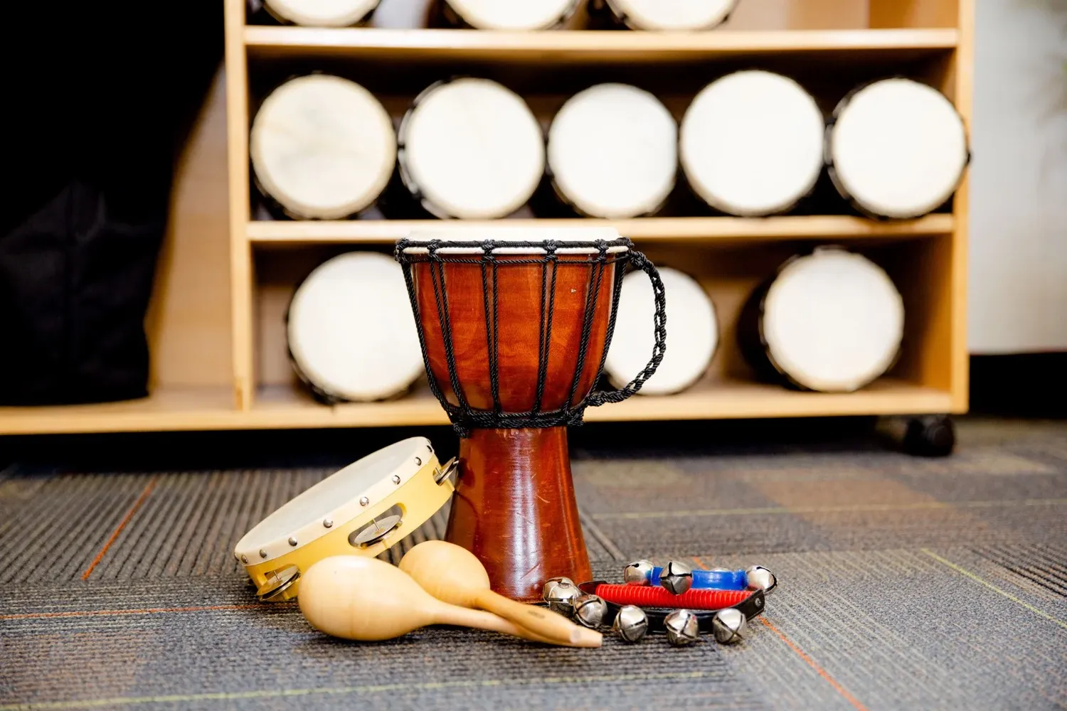 Musical instruments including drums and percussion laid out on carpet floor.