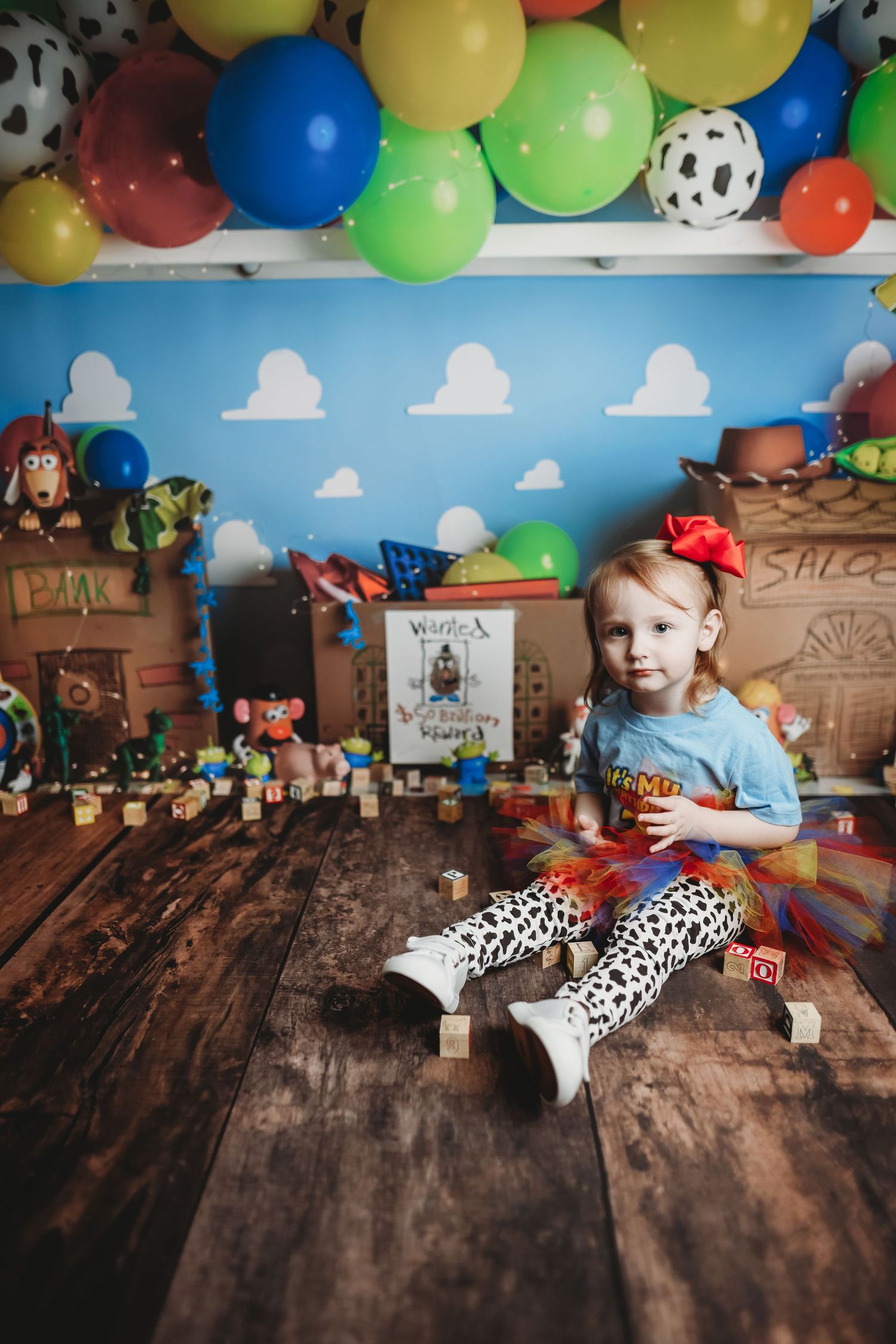 Colorful balloon arch decorates a rustic wooden backdrop with toy accents in a playful party setting.