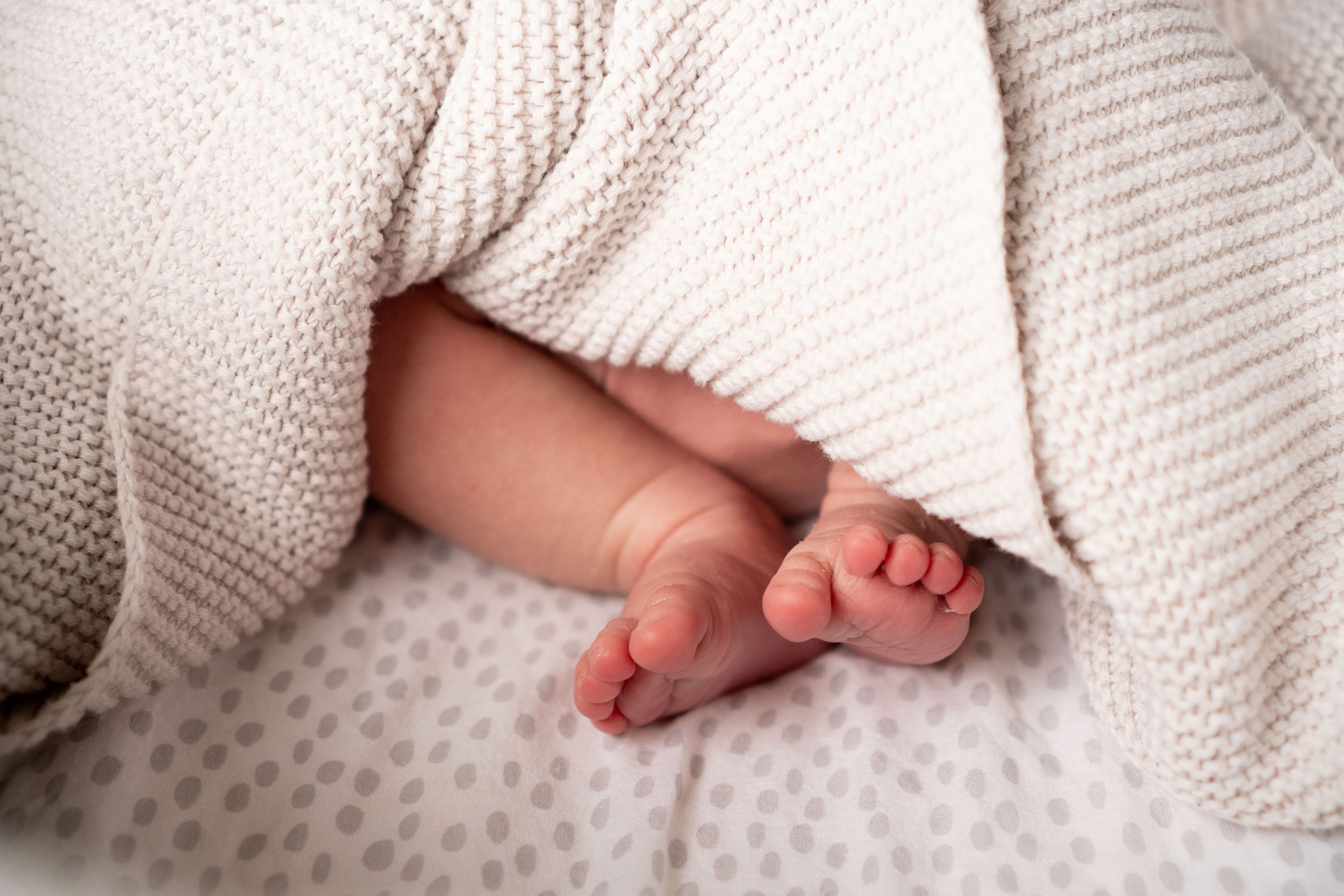 Newborn baby's toes peeping out from beneath a blanket