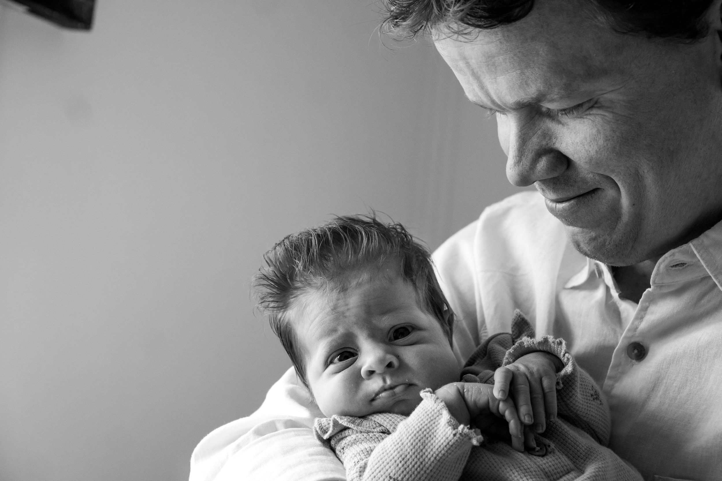 Father smiling down at newborn baby's expressive face