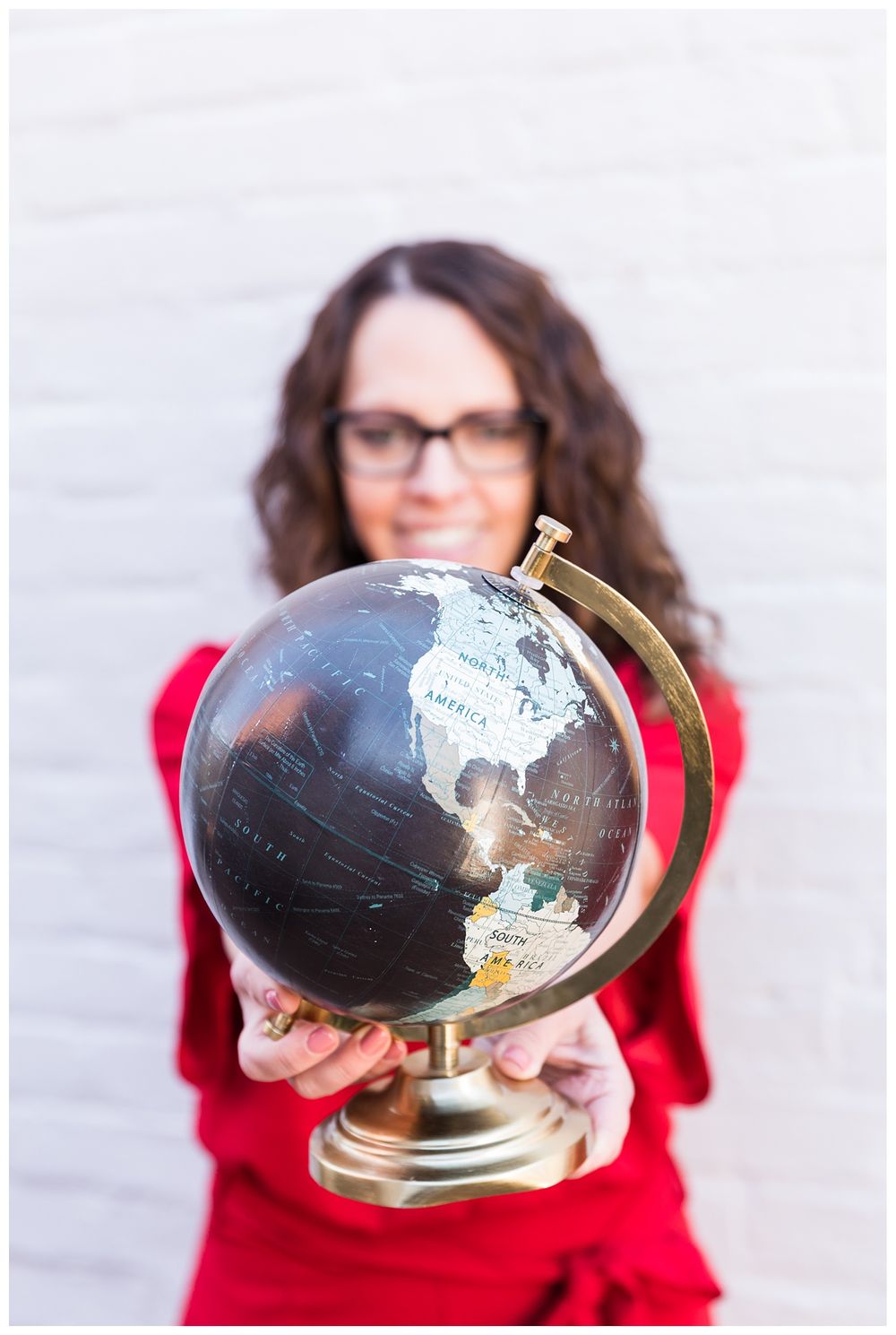 Woman posing in red outfit holding globe