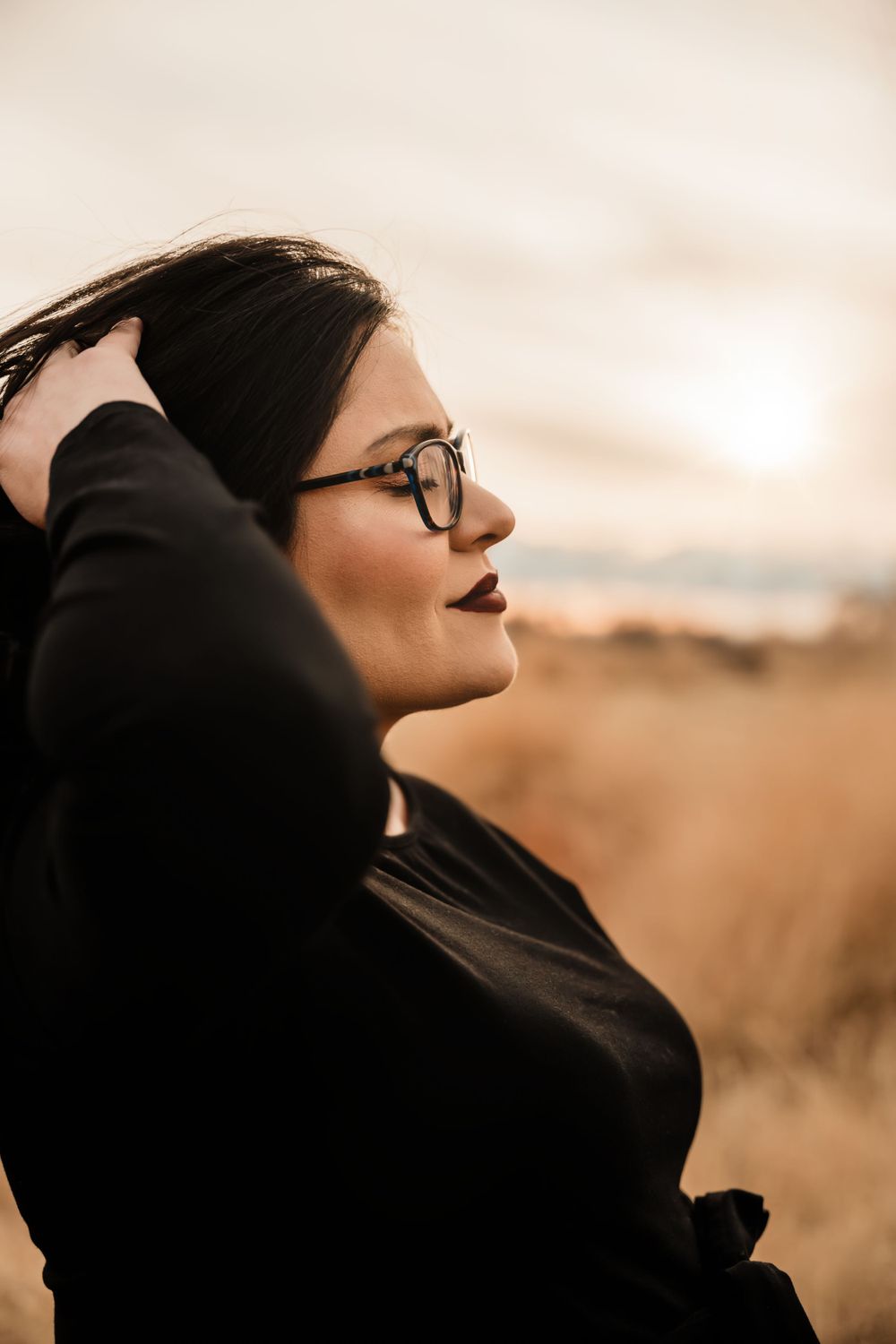 Side profile portrait in warm autumn lighting wearing black clothing and glasses.