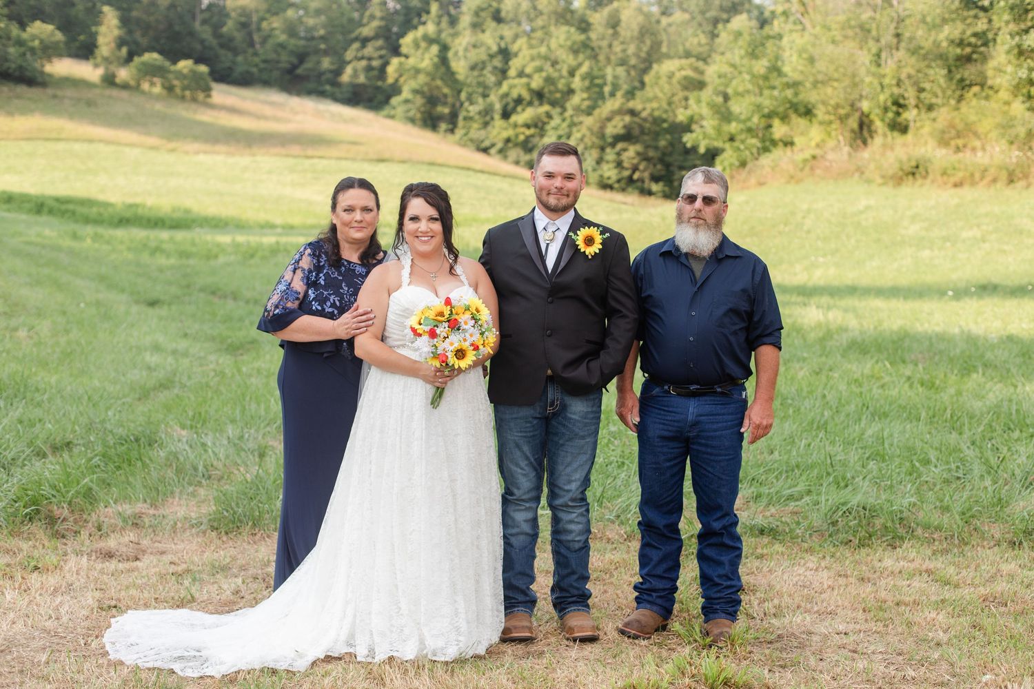 Wedding party members gathered on a grassy field for formal photos.