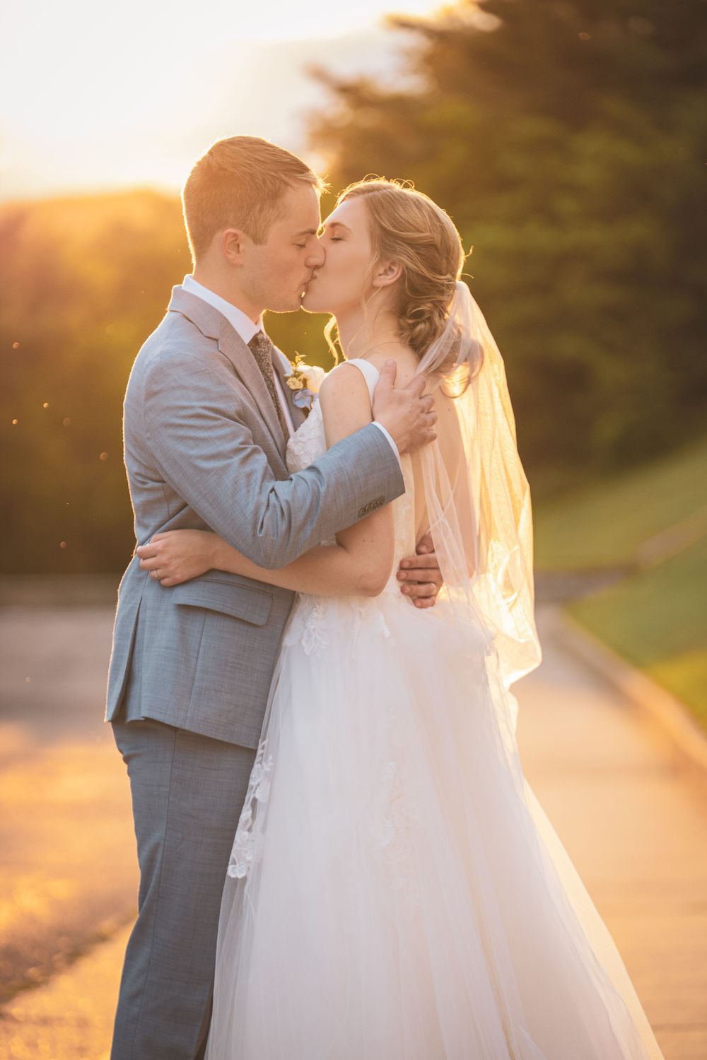 Newlywed couple shares romantic kiss during golden hour wedding photoshoot.