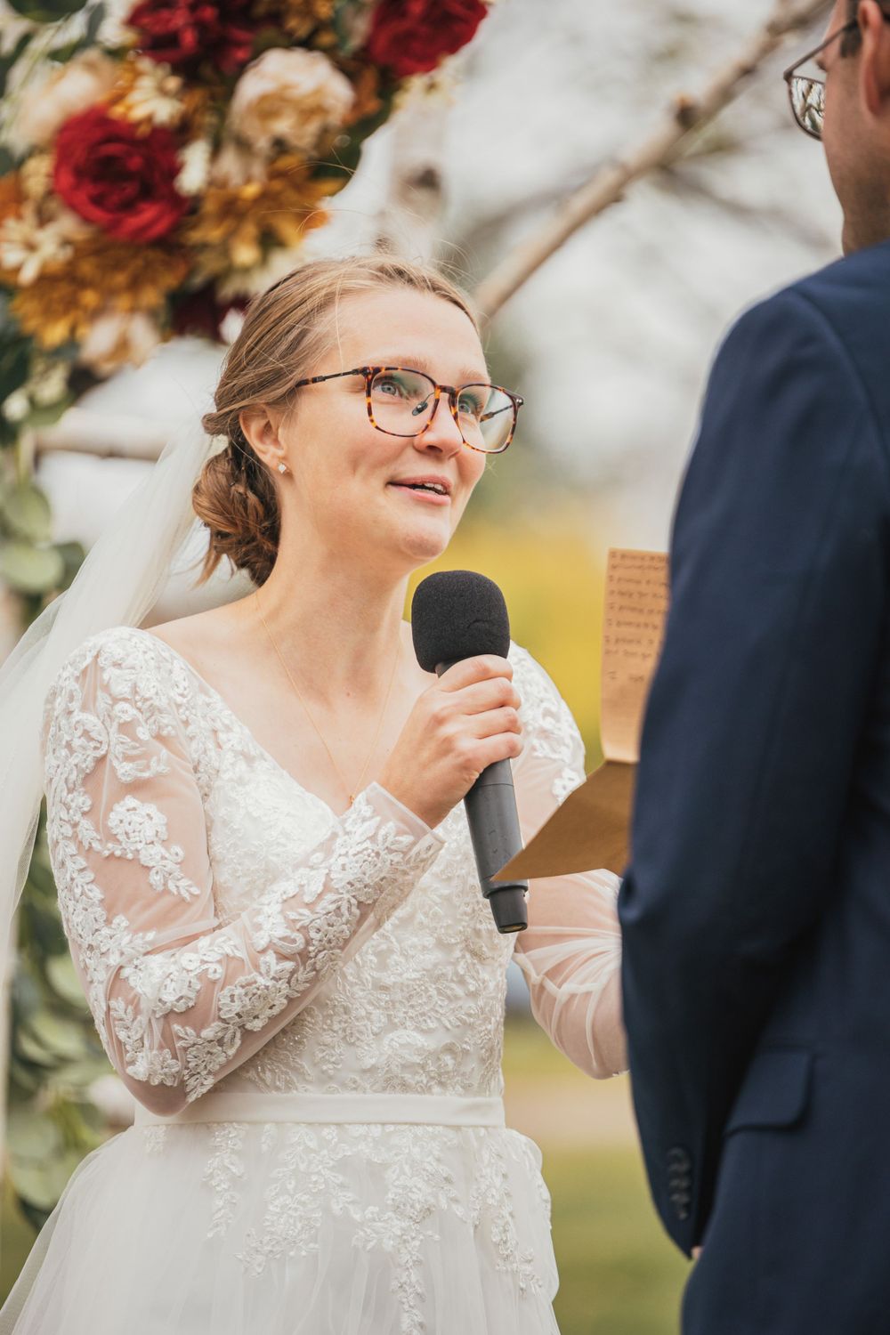 Close up of bride speaking into microphone during outdoor wedding ceremony.