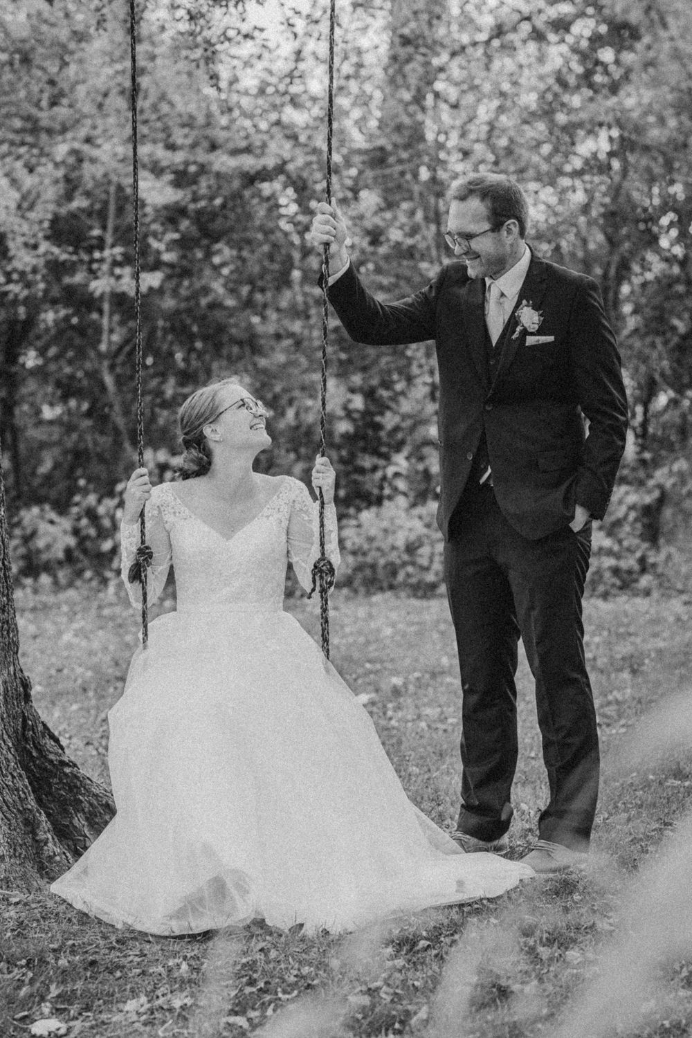 Black and white photos of couple on swing set during wedding photoshoot.