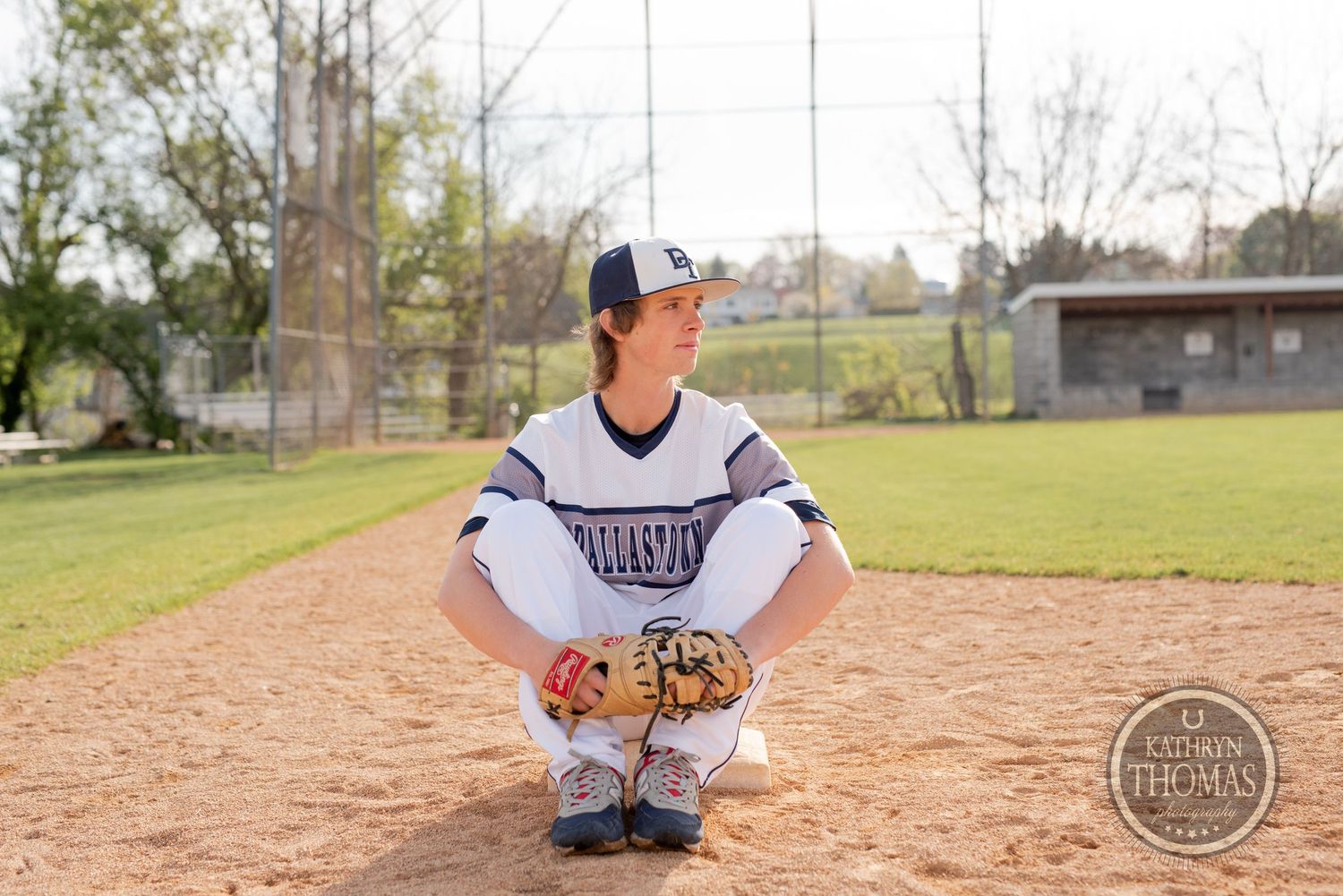 Baseball player in uniform crouches on infield dirt during practice.