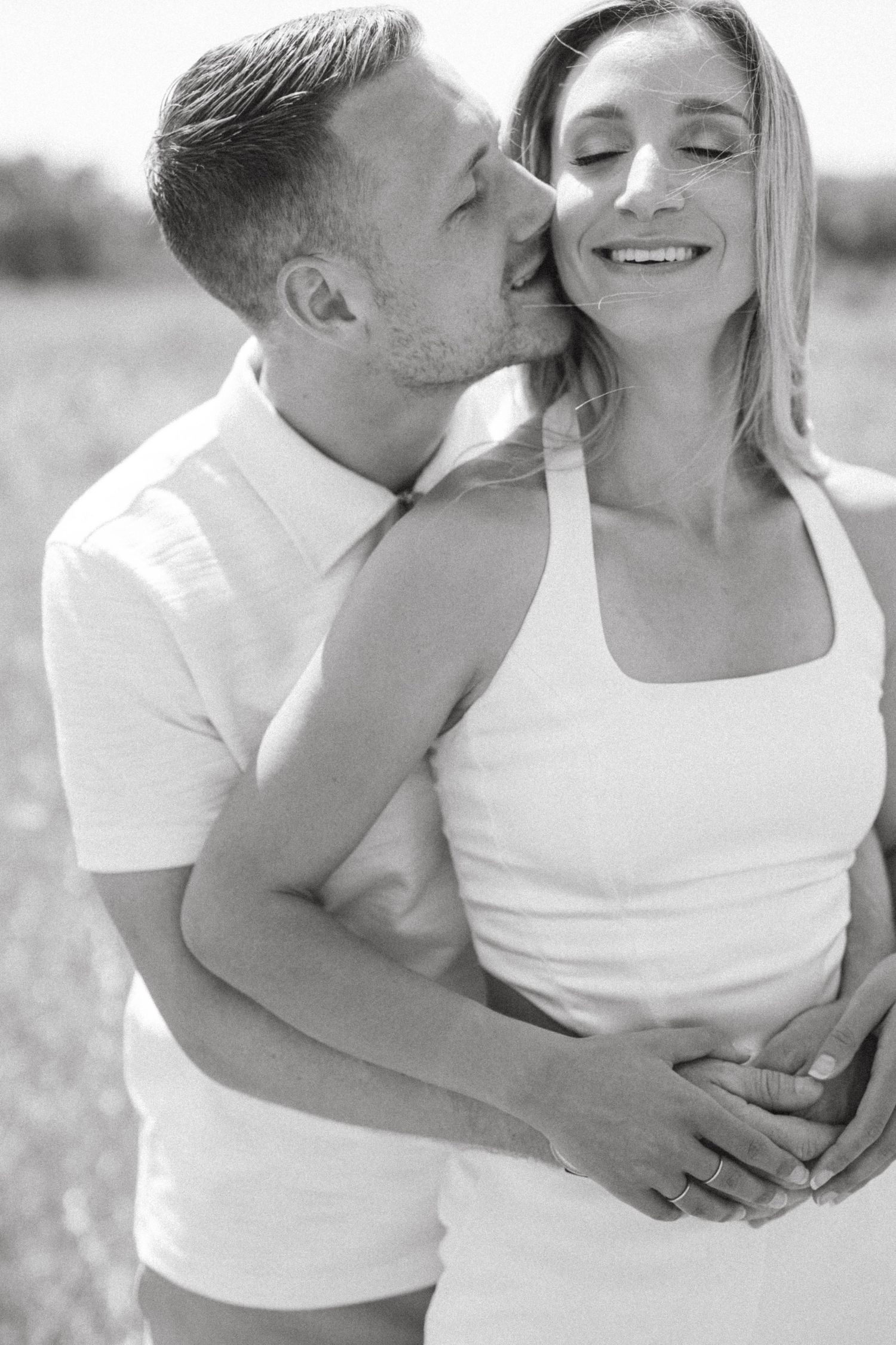 Intimate black and white portrait of a couple sharing an affectionate moment outdoors.