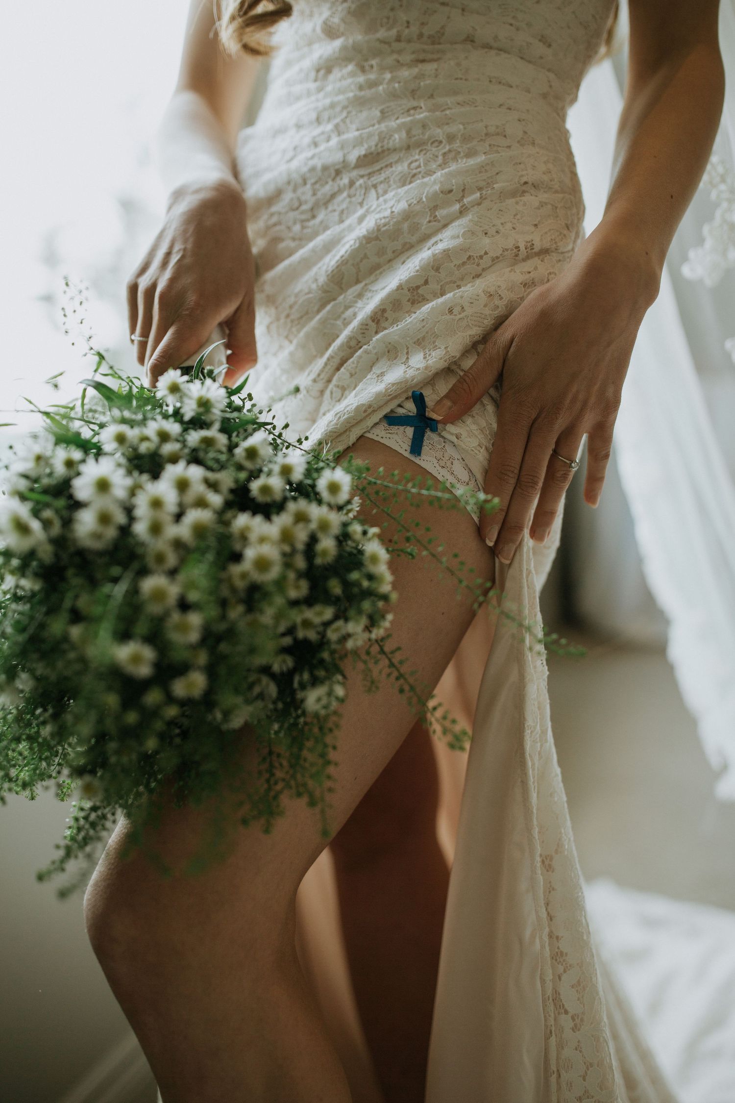 A delicate white floral wedding bouquet rests against the flowing fabric of a wedding dress.