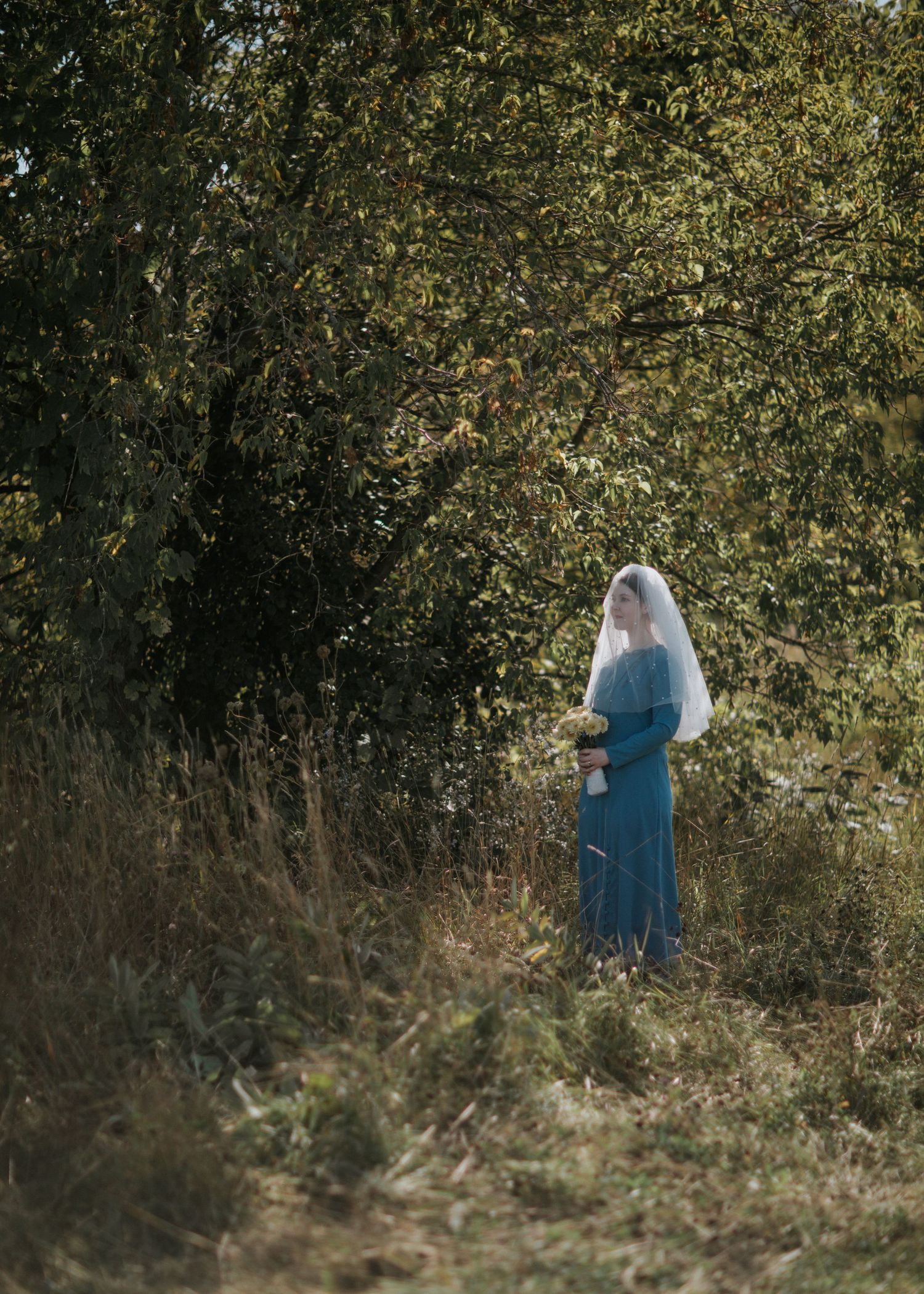 Silhouette of a figure in blue against natural foliage backdrop.