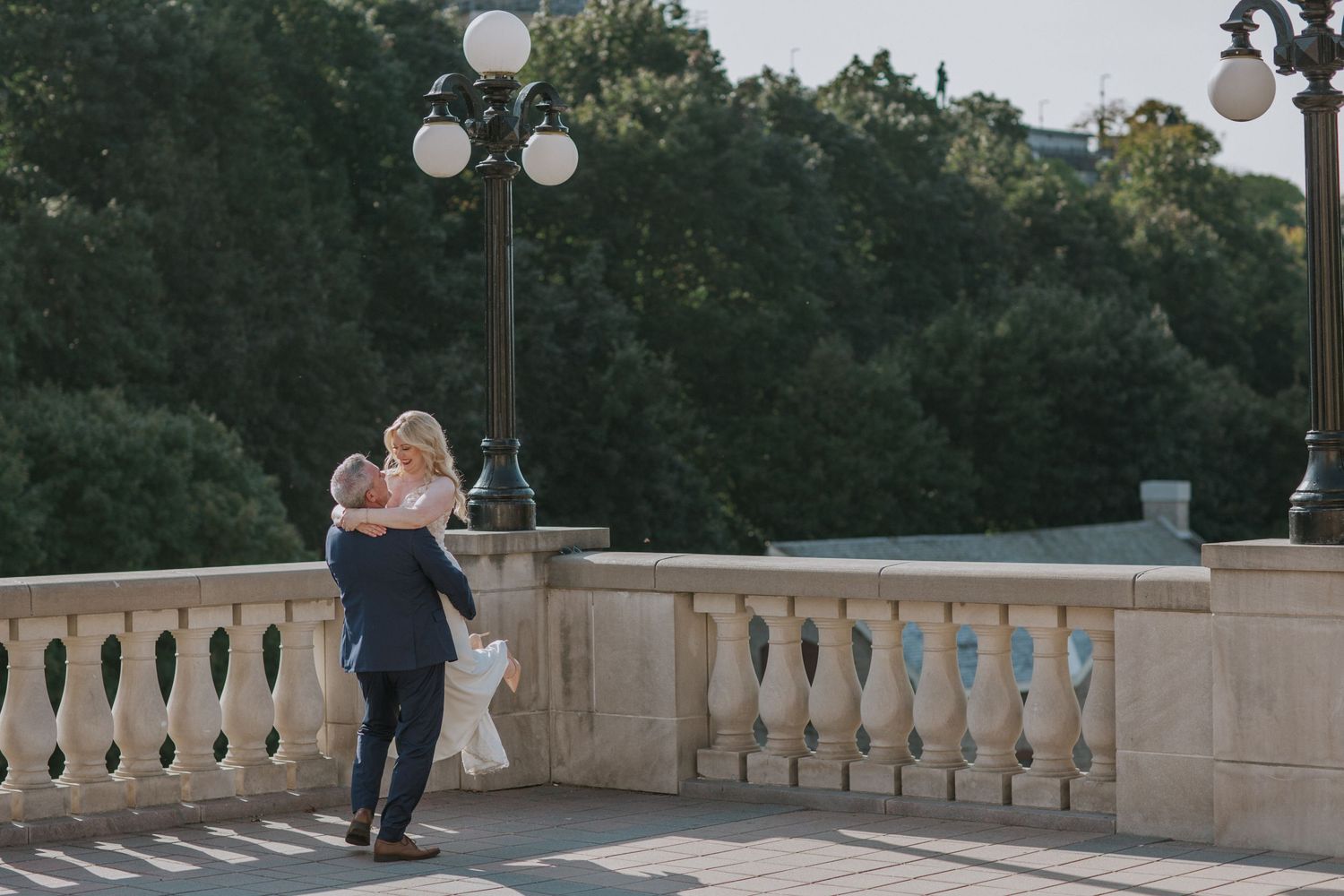 A couple shares an intimate dance on an elegant stone terrace with lamp posts.