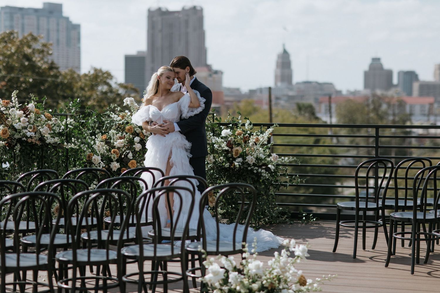 Urban wedding scene with skyline and decorative railings in background.