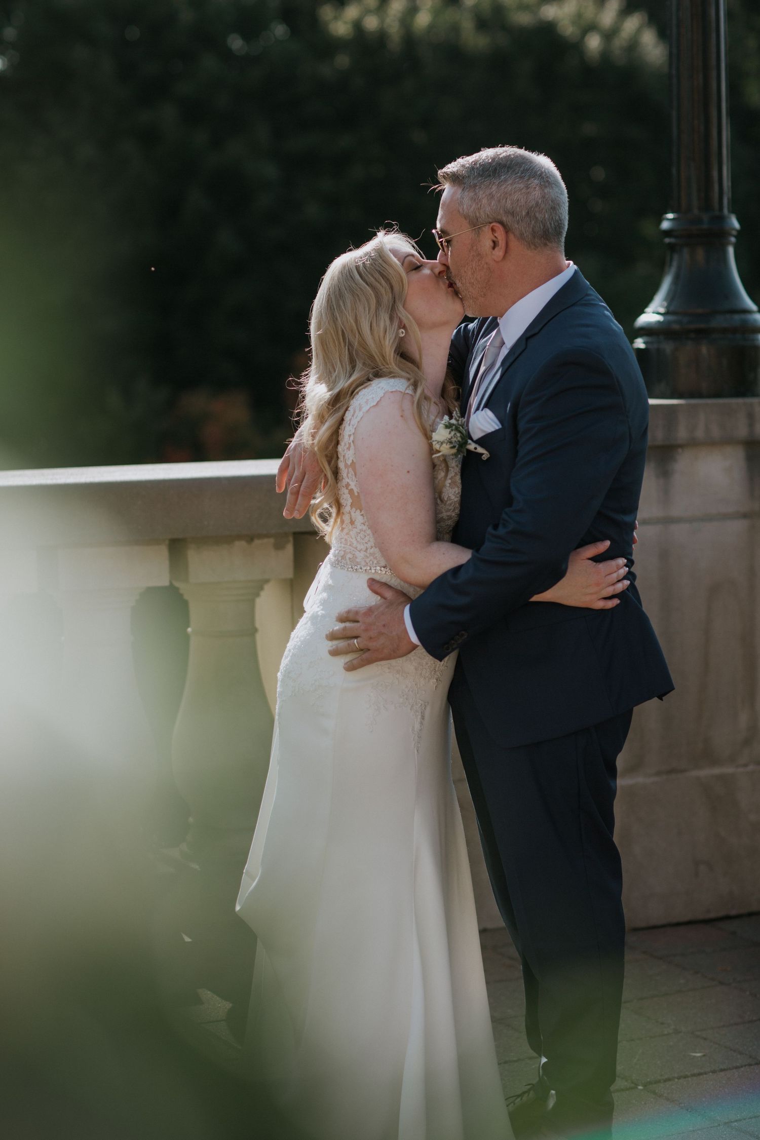 A romantic wedding moment captured on an elegant stone balcony with soft lighting and natural surroundings.