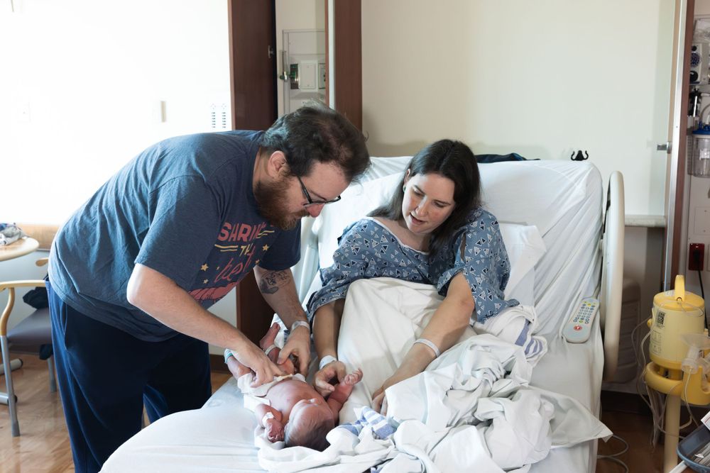 Hospital scene showing parents tending to their newborn baby.