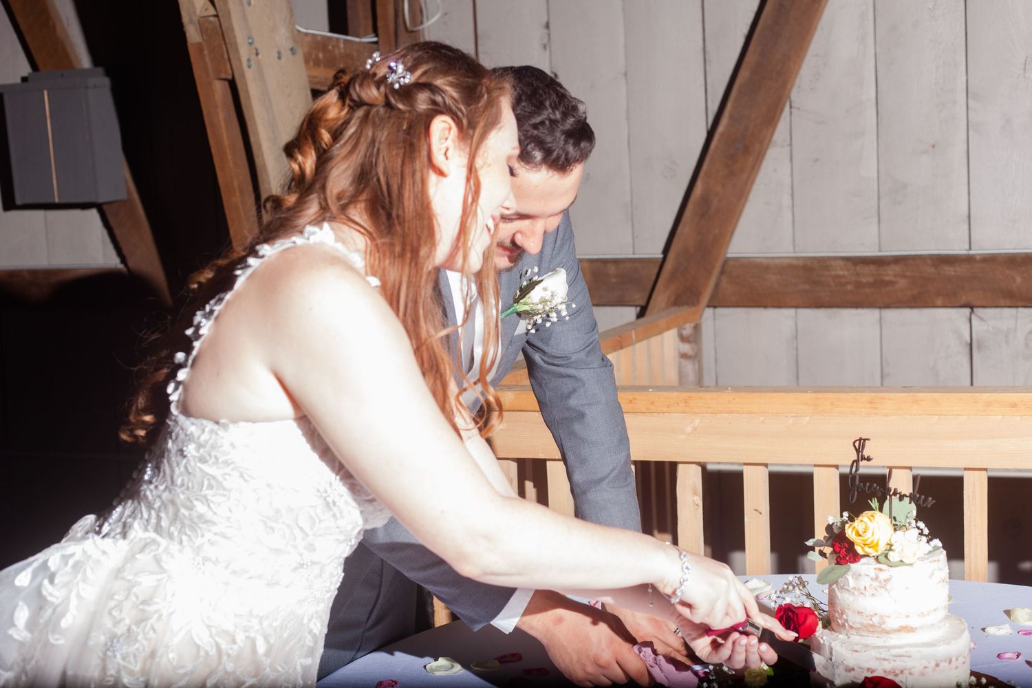 A rustic indoor wedding reception scene with cake cutting decor and wooden details.