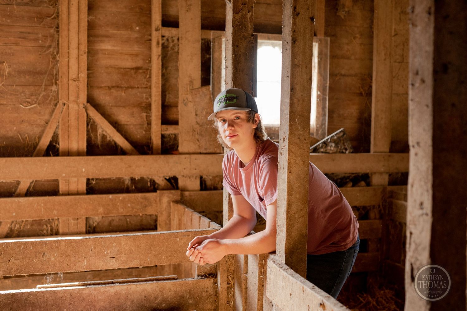 Person in pink shirt tends to livestock inside wooden barn structure.