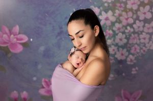 Artistic maternity portrait with pink floral backdrop and soft lighting.