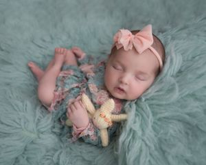 Dreamy newborn portrait on seafoam textured backdrop with vintage plush toy.