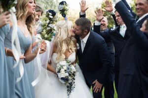 Joyful wedding party celebration outdoors with light blue bridesmaid dresses.