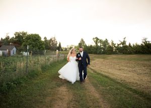 Wedding party walking through rustic field at sunset creating silhouettes.