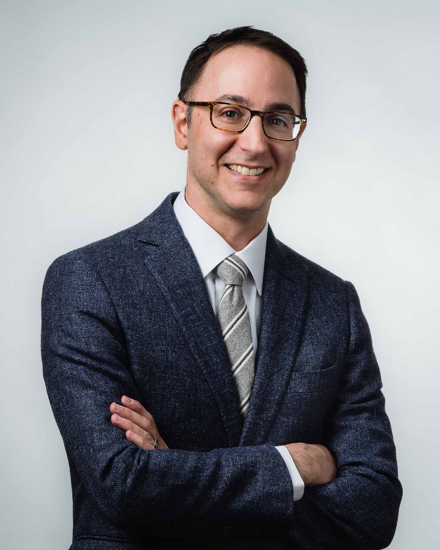 professional headshot of Seattle financial services executive wearing suit and glasses with arms crossed