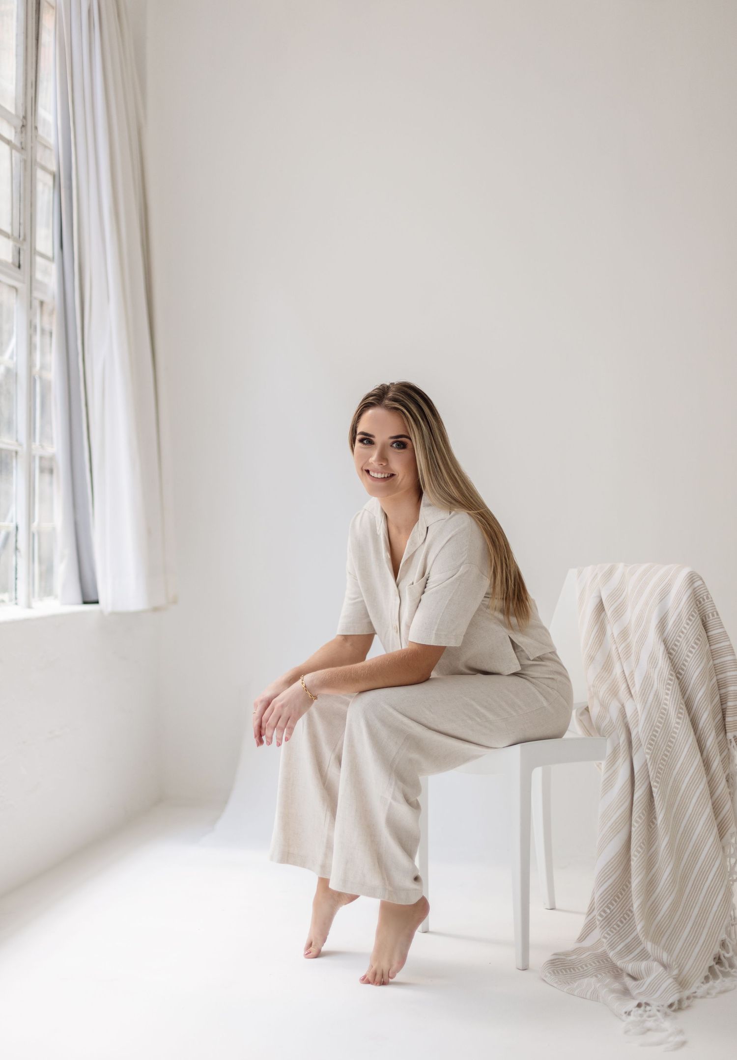 Minimalist portrait in all-white room featuring cream colored loungewear.