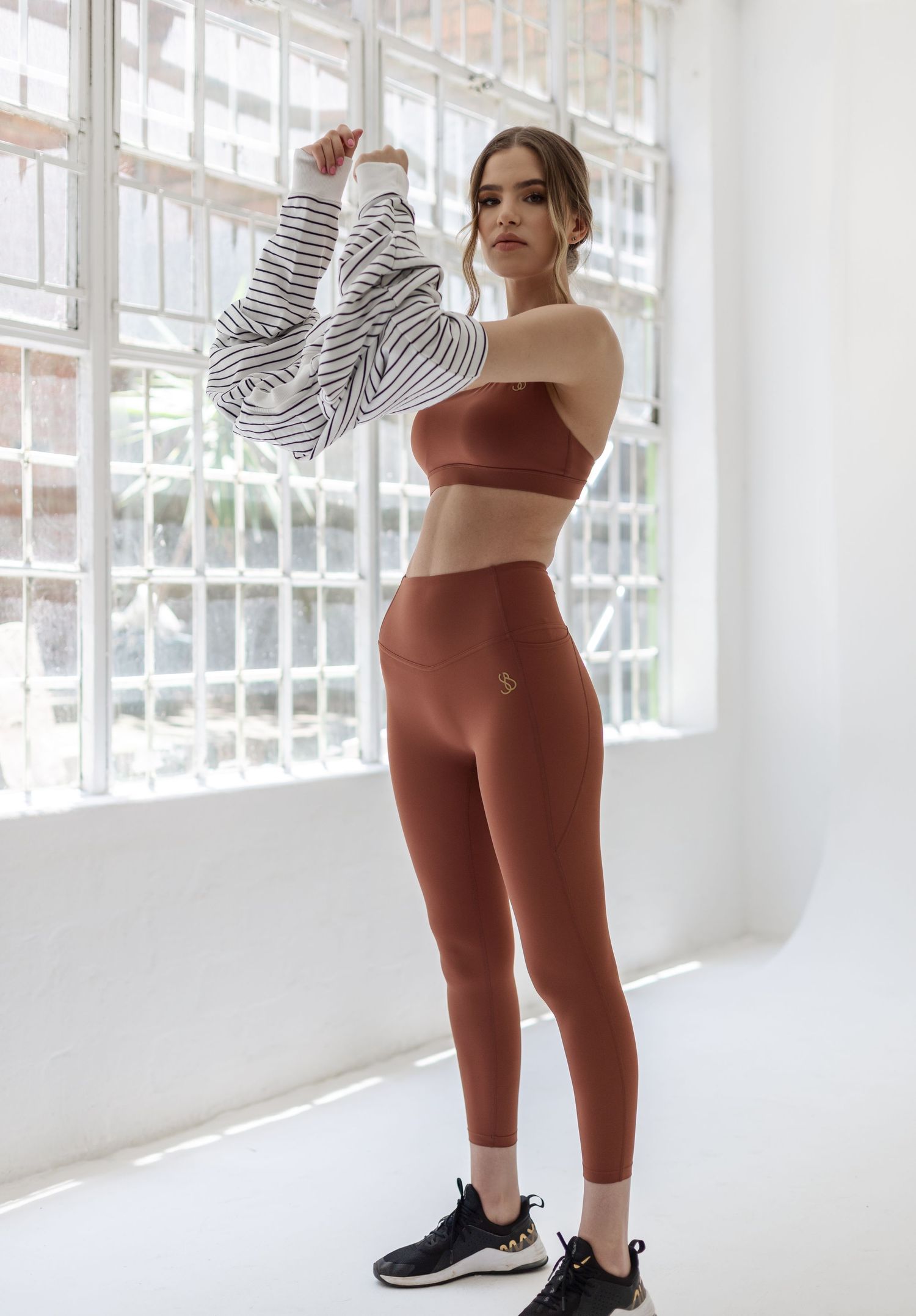 Athletic wear ensemble with brown crop top, leggings and striped oversized jacket.