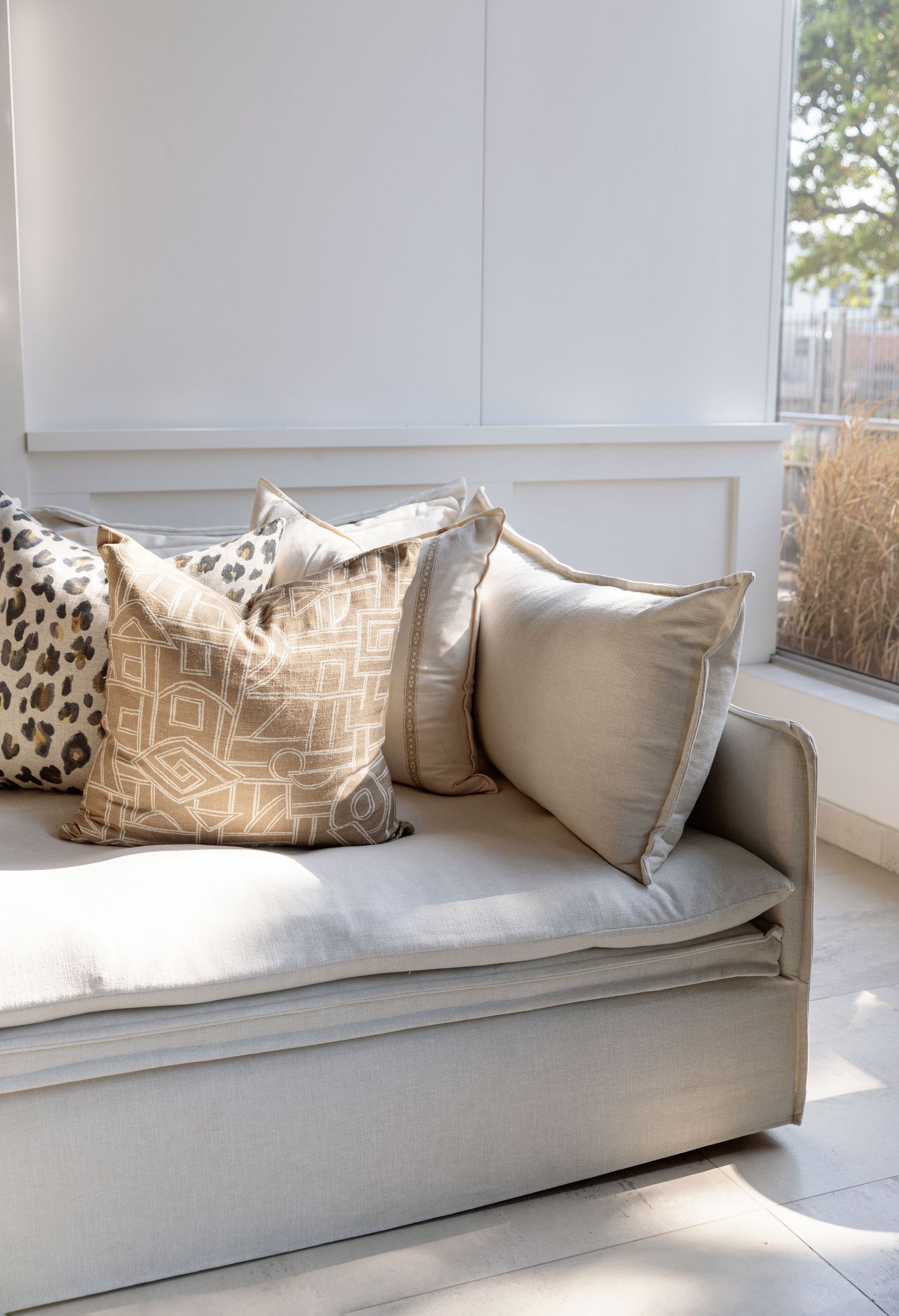Cozy window seat with neutral throw pillows featuring leopard and geometric patterns.