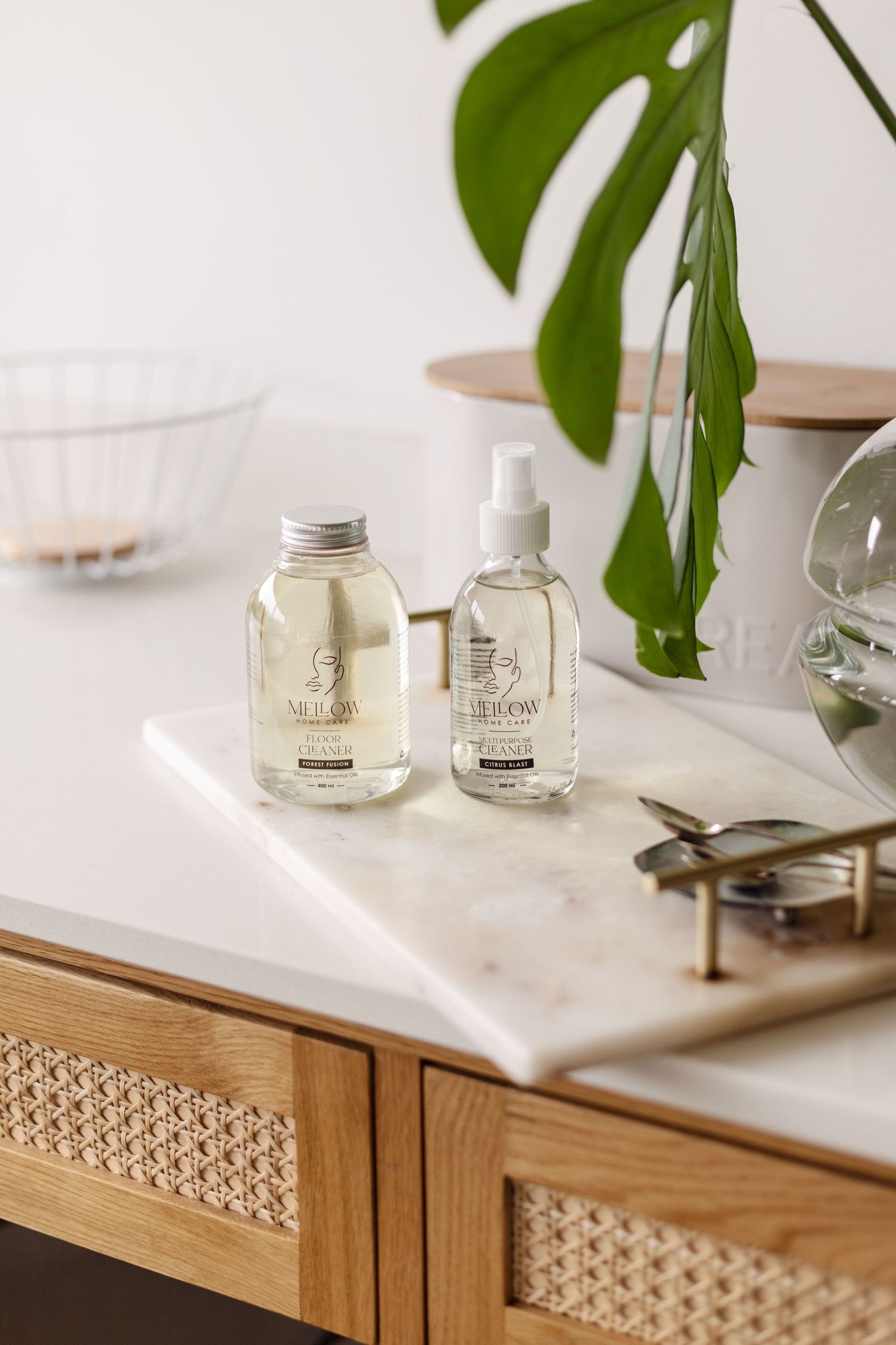 Minimalist bathroom products on marble counter with monstera plant leaf.