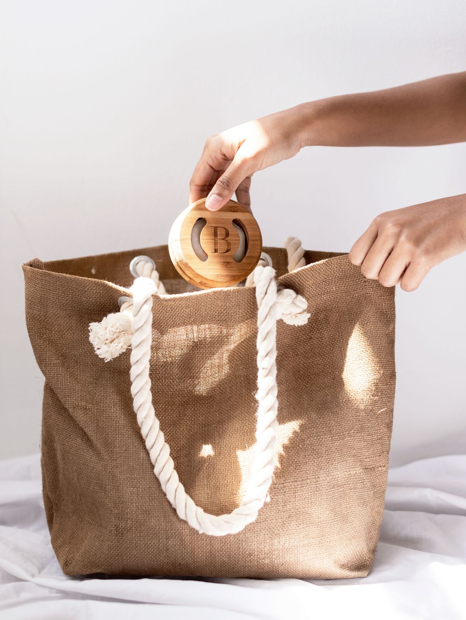 Brown canvas tote bag with rope handles and circular wooden detail being opened.