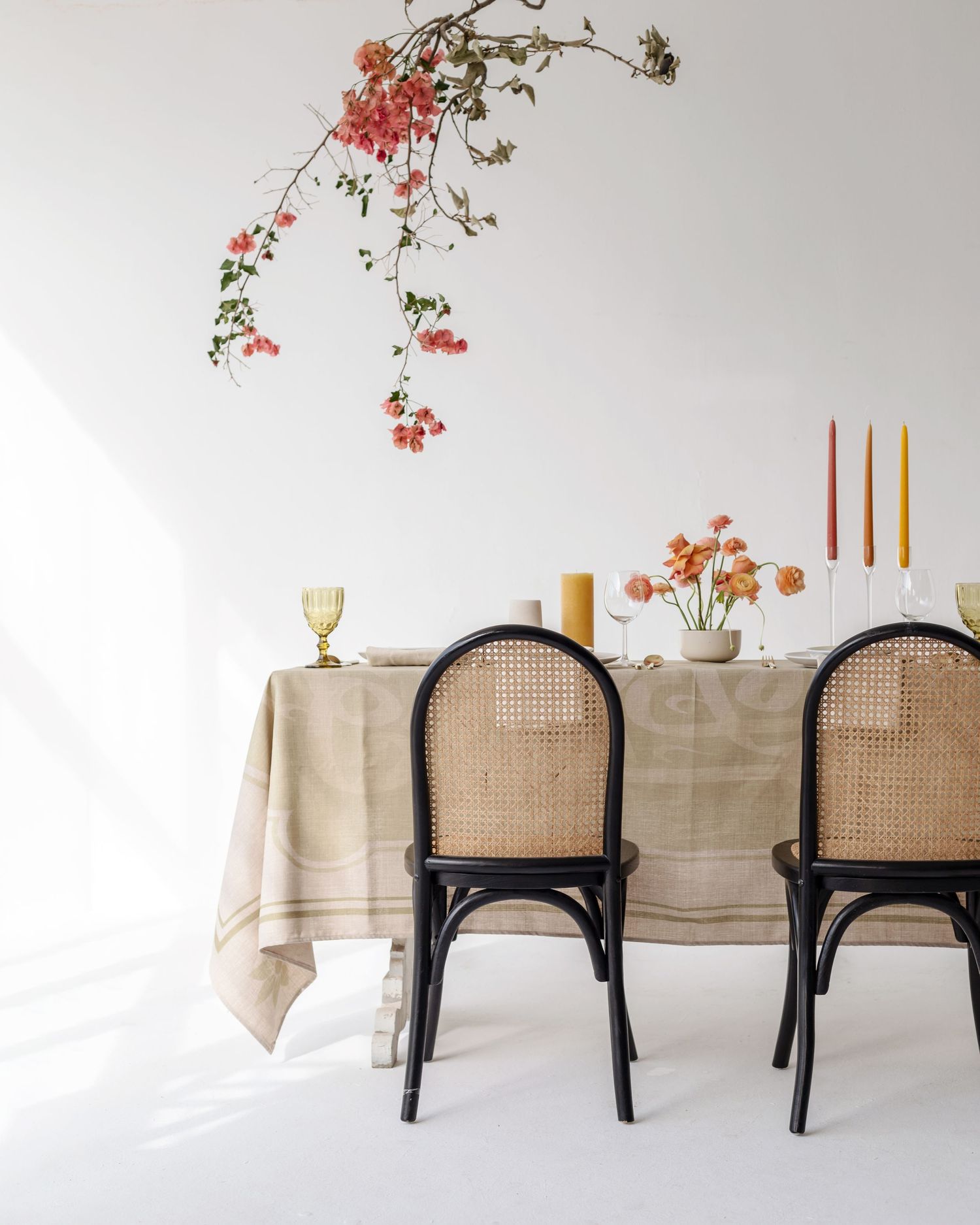 Minimalist dining table with cane chairs, coral flowers and taper candles creating a romantic atmosphere.