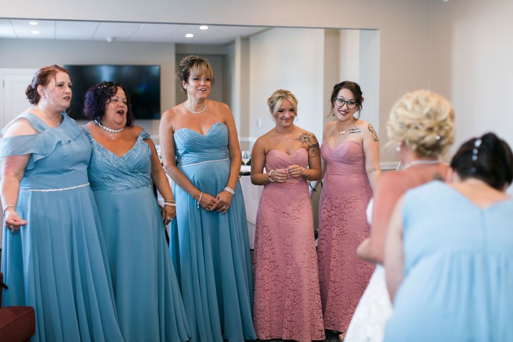 Bridesmaids in blue and pink dresses standing together during wedding preparations.