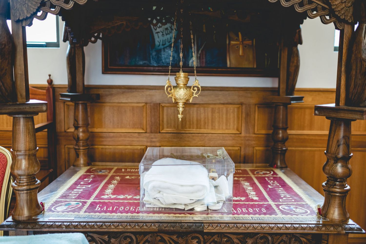 Traditional church altar setup with white cloth on red decorative fabric.