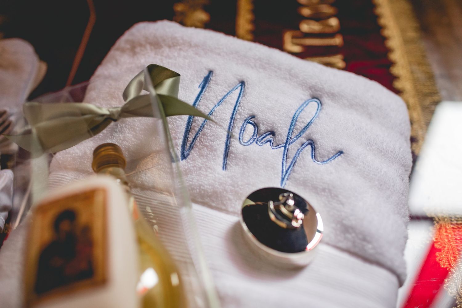 Close-up of embroidered 'Noah' text on white fabric with religious imagery in background.