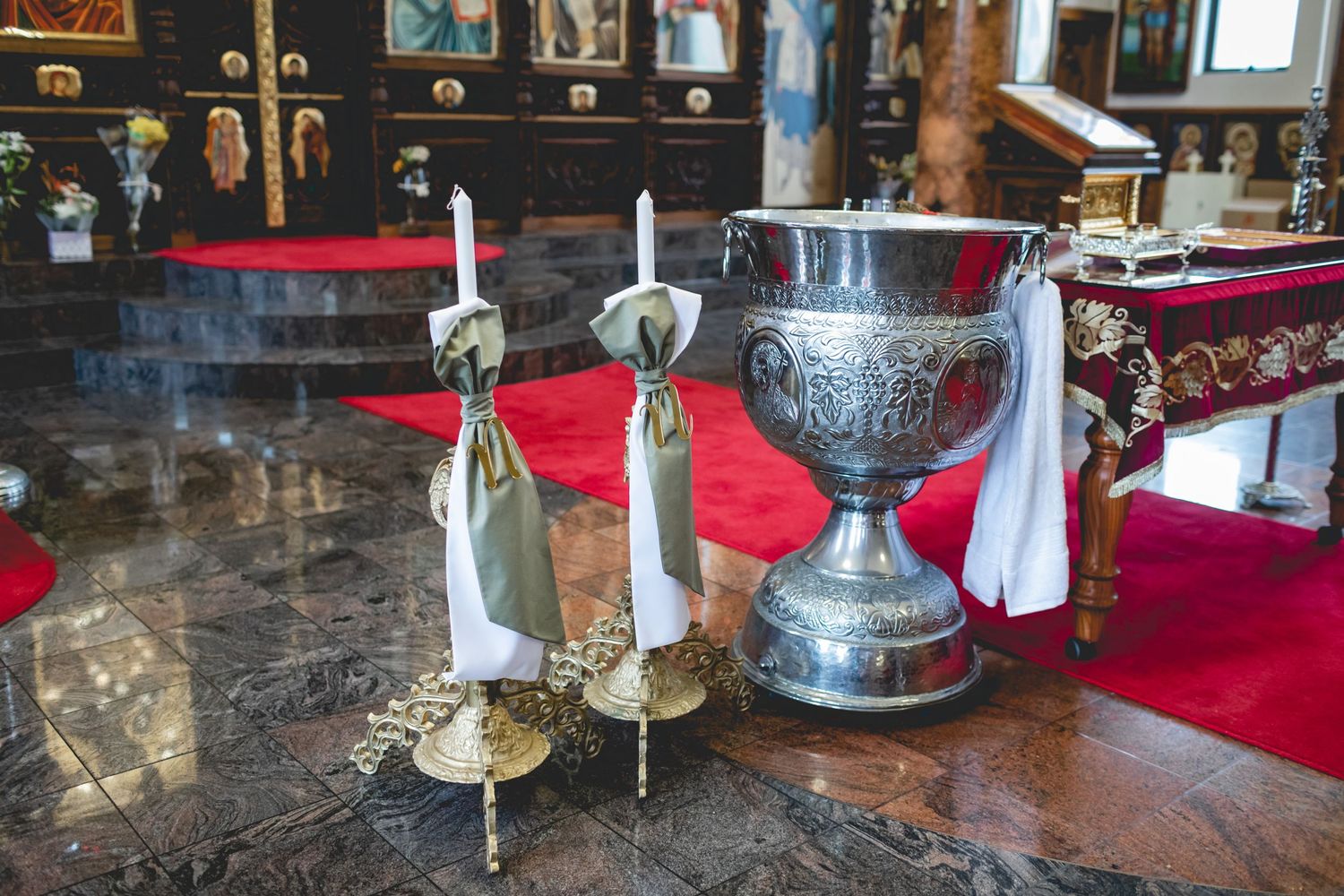 Ornate silver chalice and candles displayed on altar with red cloth at traditional church ceremony.