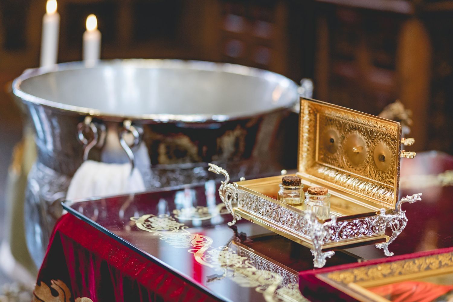 Ceremonial items including silver bowl and ornate wooden box displayed on red velvet cloth.