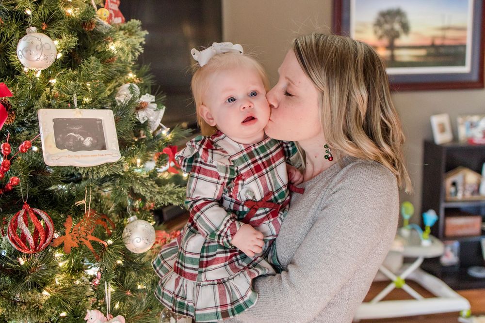 mom kissing baby by the christmas tree