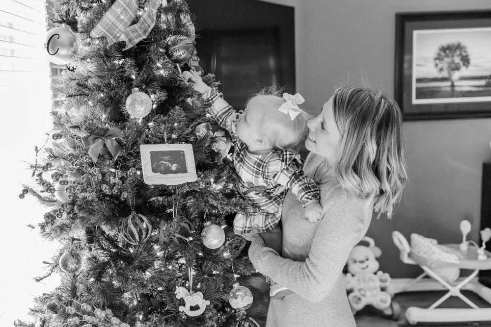 mom and baby reaching for ornament on the christmas tree