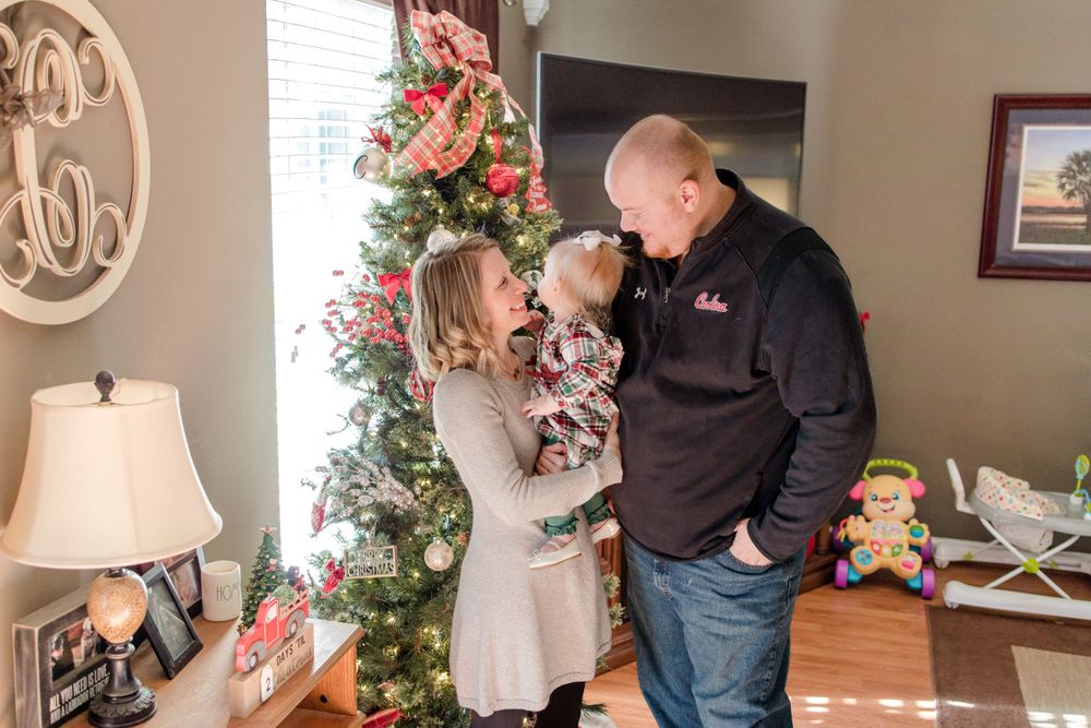 mom and dad looking at baby by the christmas tree