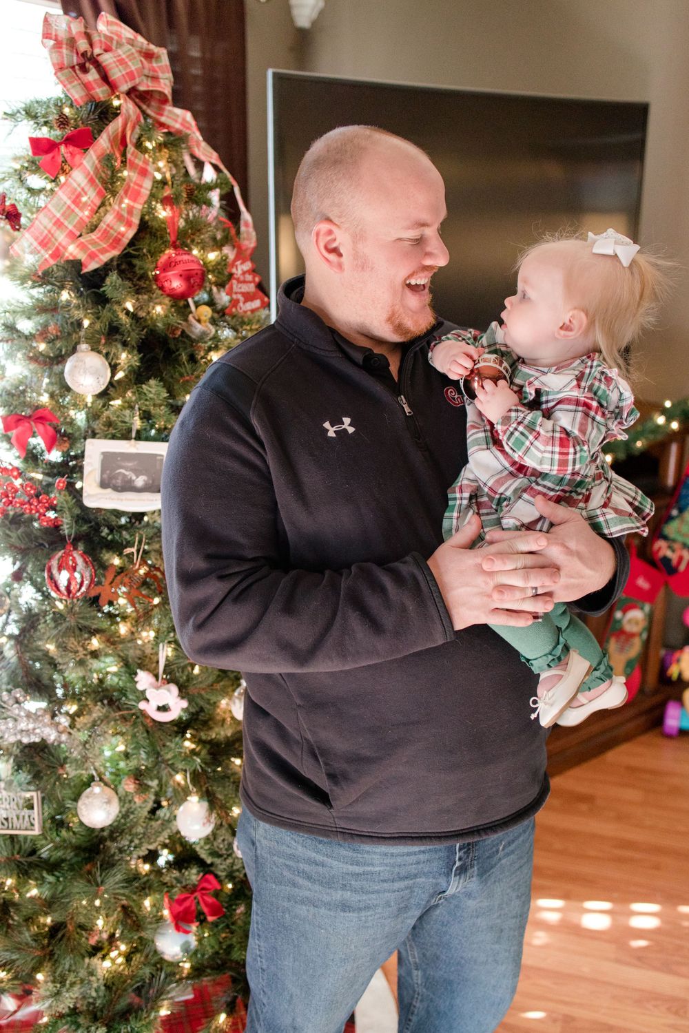 dad looking at baby by the christmas tree