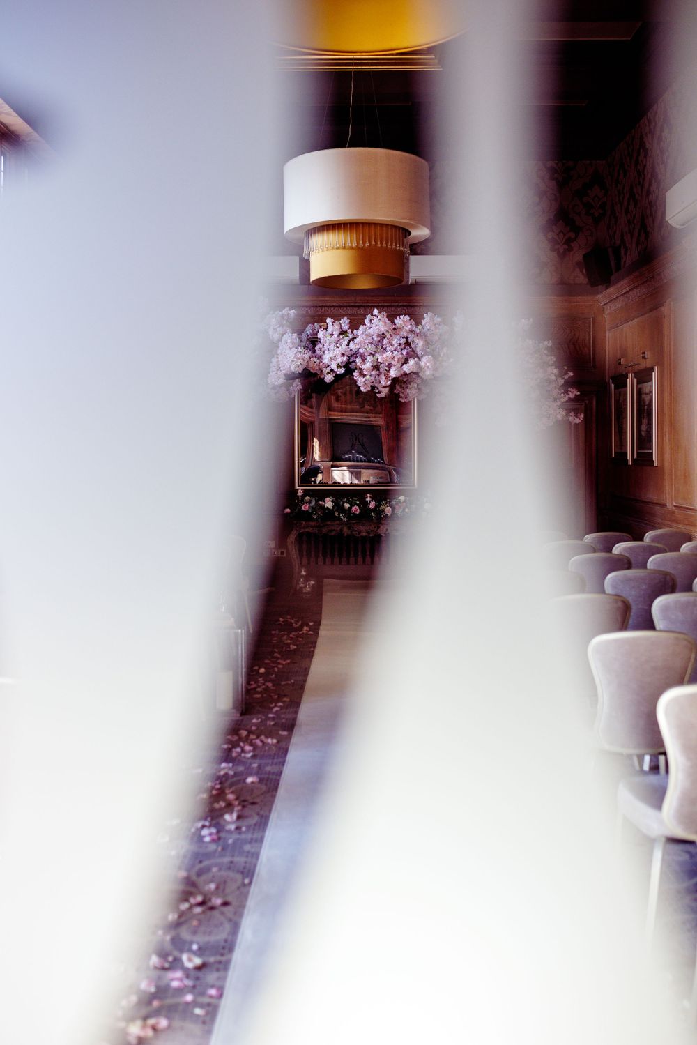 Artistic wedding venue photo with soft focus showing chairs and lighting fixtures.