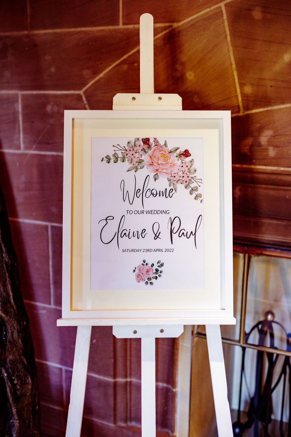 Wedding welcome sign on white easel with floral design and calligraphy.