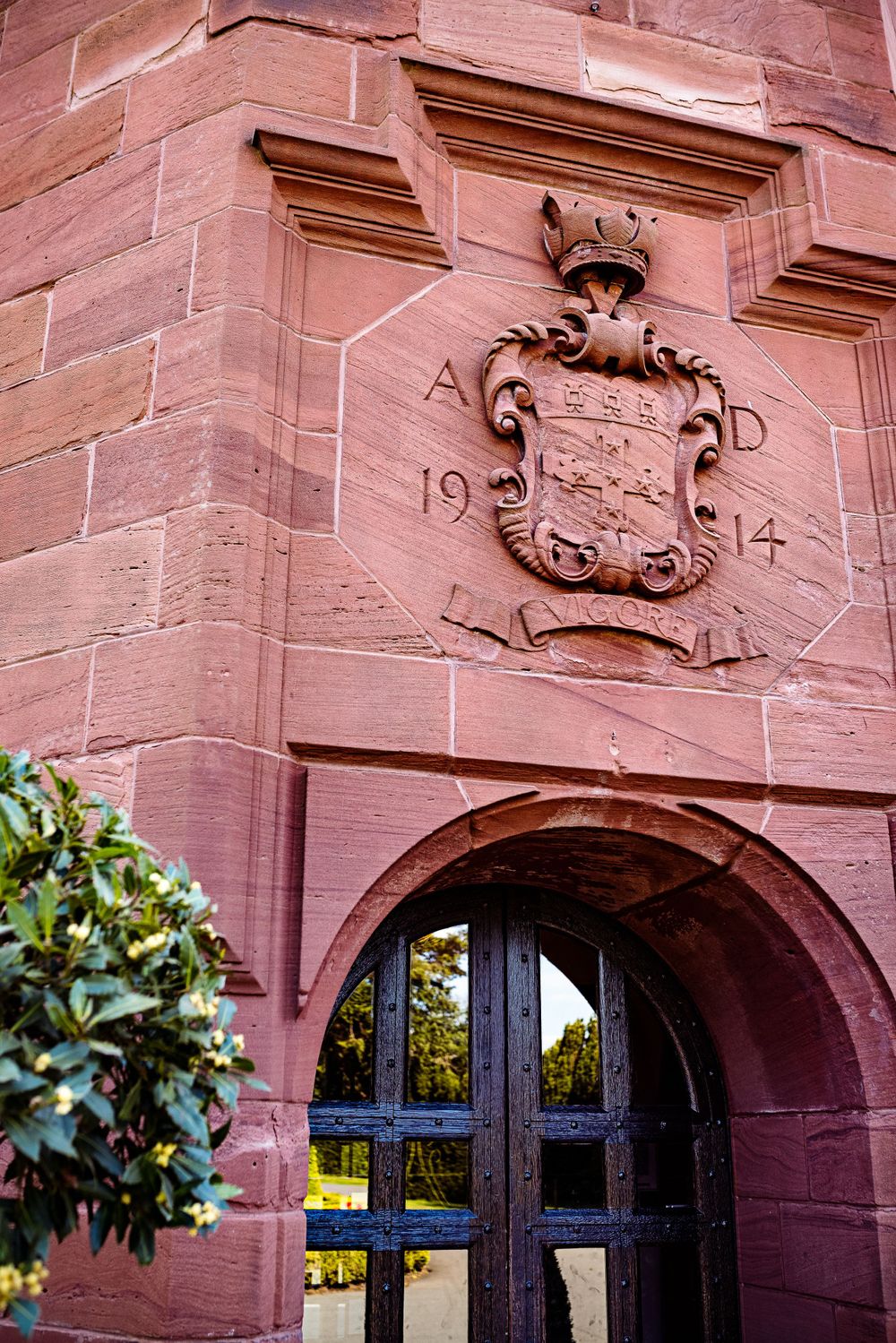 Historic carved stone doorway with decorative crest dated 1914 in red sandstone architecture.