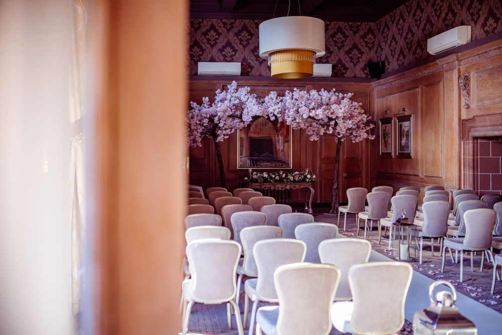 Wedding venue setup with rows of white chairs and ornate wallpaper in an elegant room.