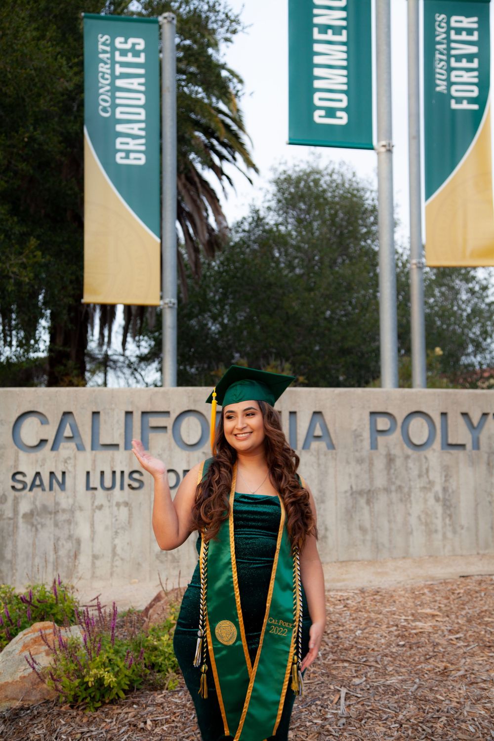 Graduate standing by Cal Poly sign.