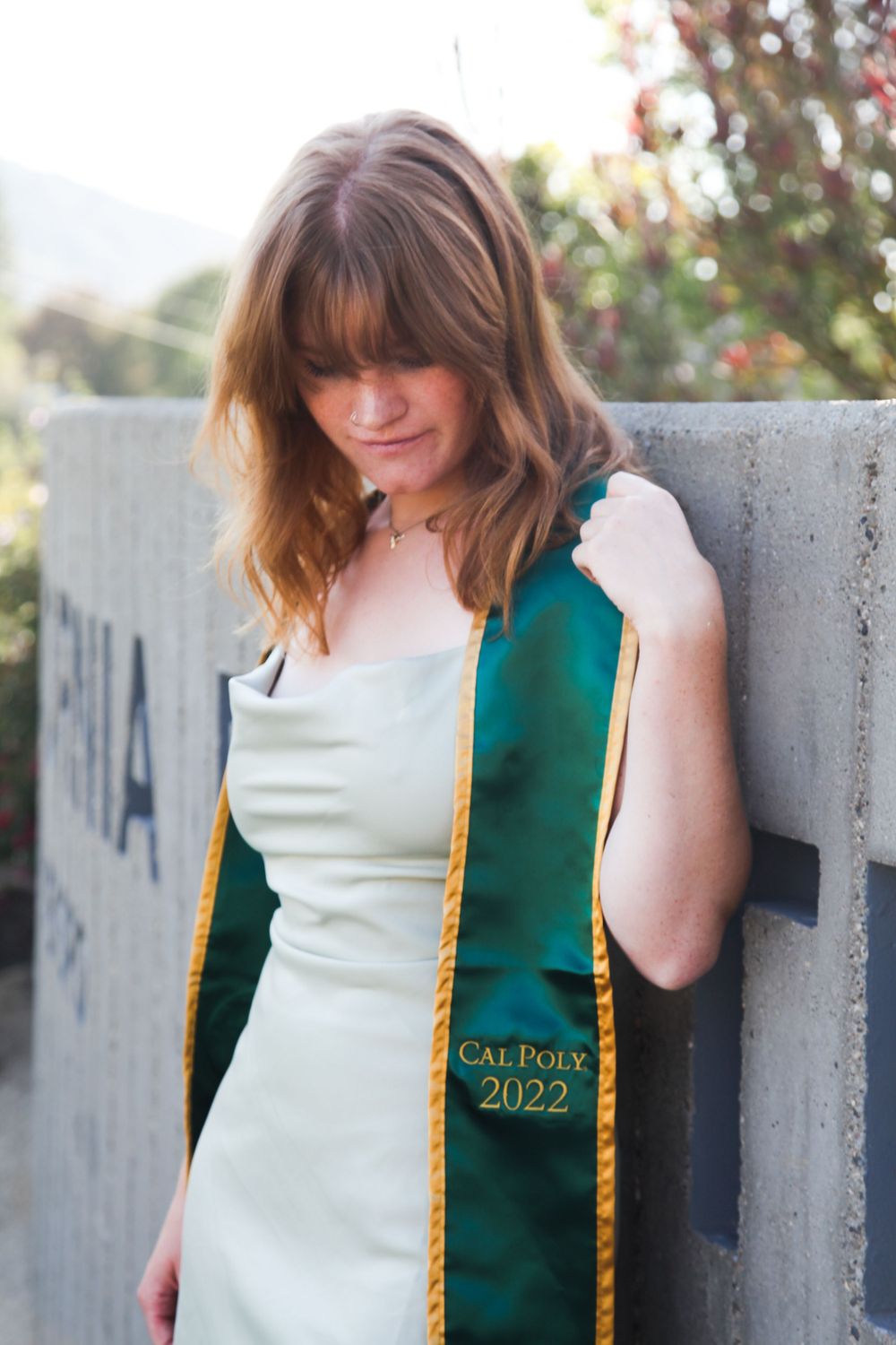 Graduate standing by Cal Poly sign.