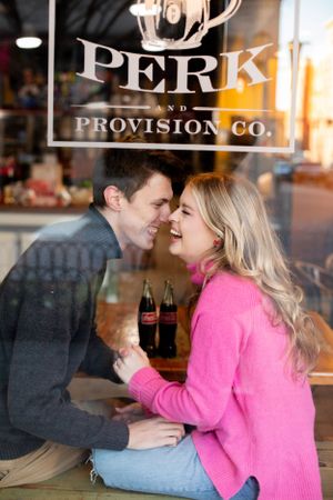 A couple sharing a sweet moment at Perk and Provision Co cafe with Coca-Cola bottles on the table.