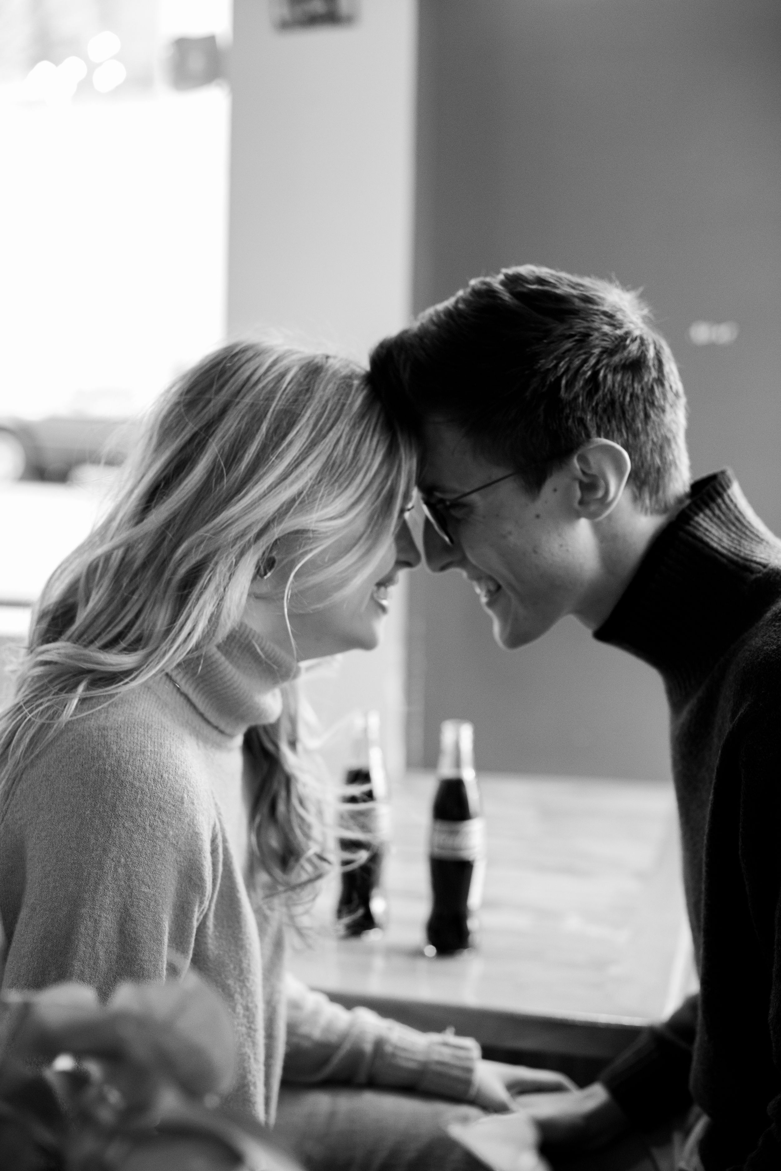 A romantic black and white photo of a couple sharing an intimate moment with Coca-Cola bottles in the background.