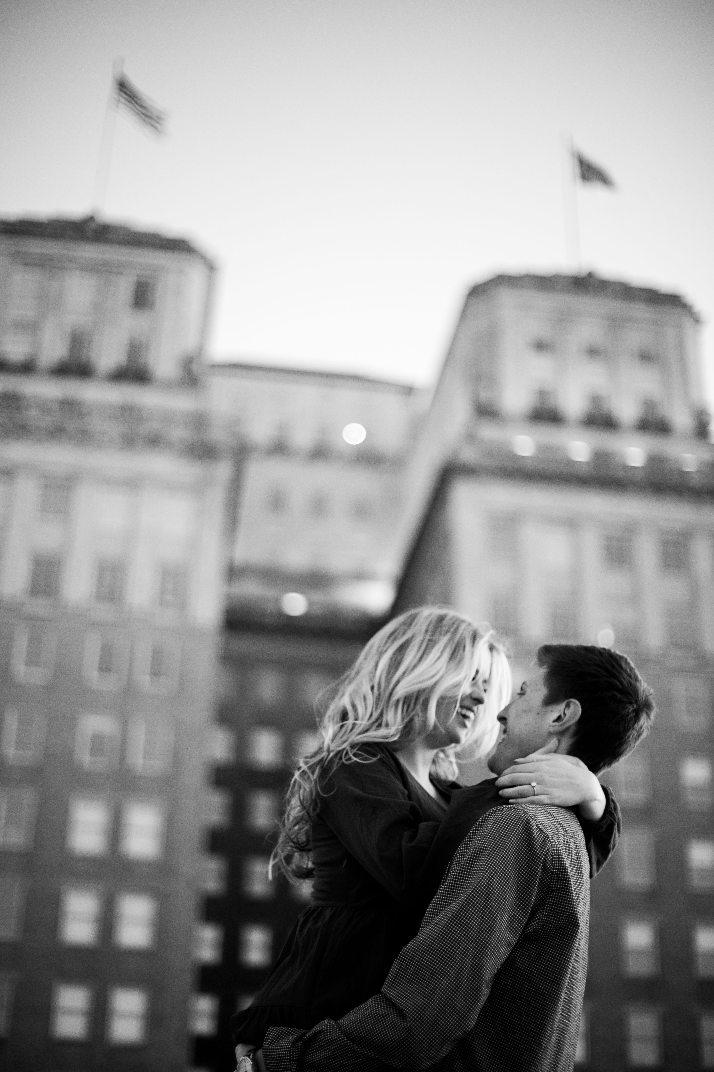 A romantic black and white kiss against a cityscape backdrop with flags flying on buildings.